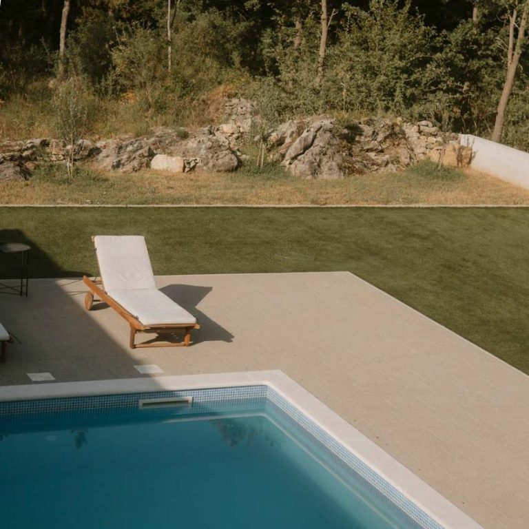 Helles Schwimmbad mit Liegestuhl auf der Terrasse umgeben von inspirierender Natur.